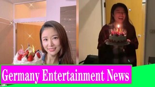 46 year old Ruby Lin celebrates her friend's birthday, holding a cake with a smile on her face, and