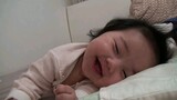 Seorang bayi kecil yang lucu yang sangat bahagia dan mengantuk pada saat yang bersamaan
