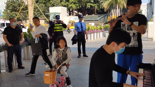 A boy plays the flute on the street, the security guards like it